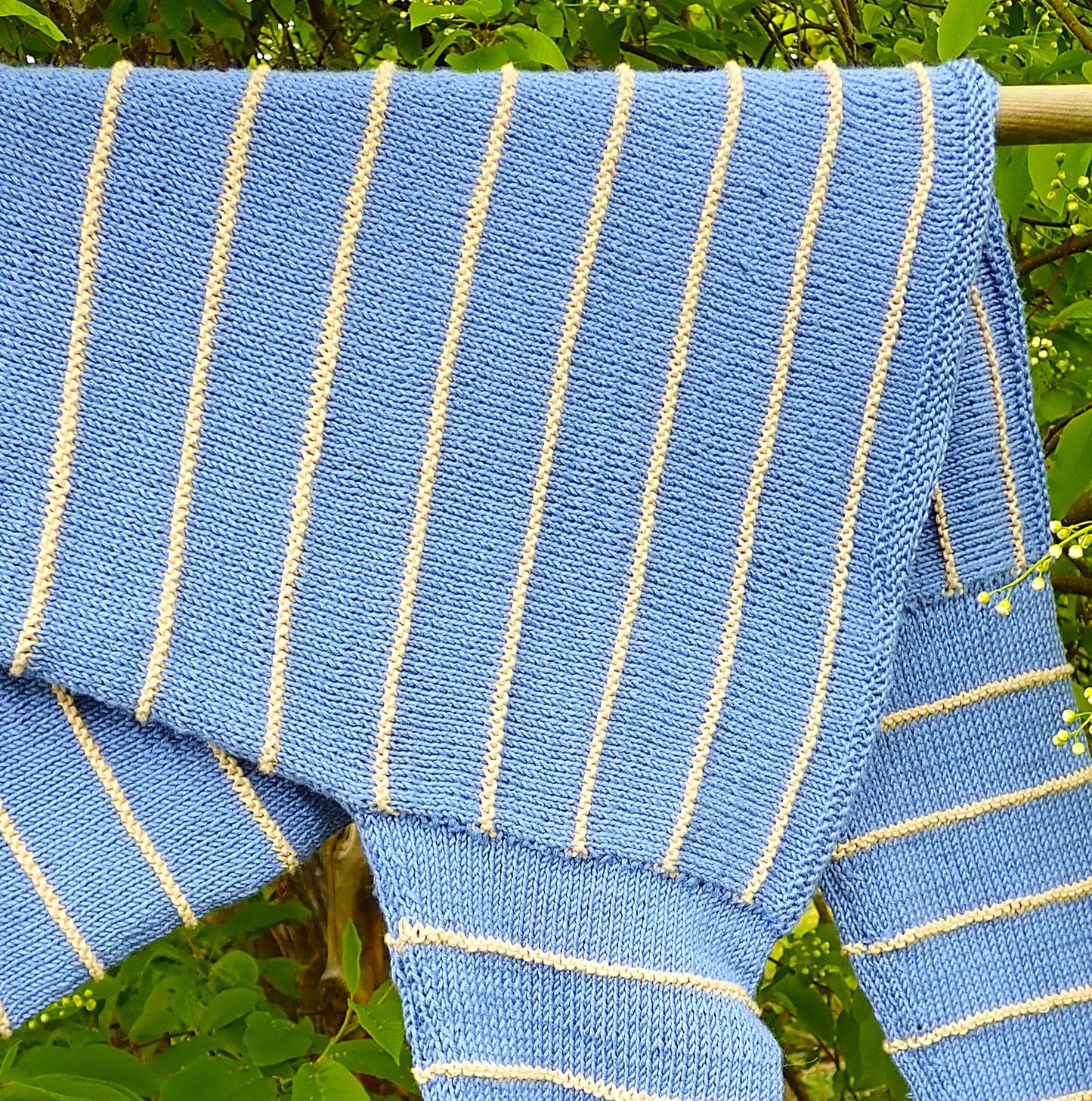 Vaaleansininen neulepusero, jossa on kapeita beigejä raitoja ja venepääntie.