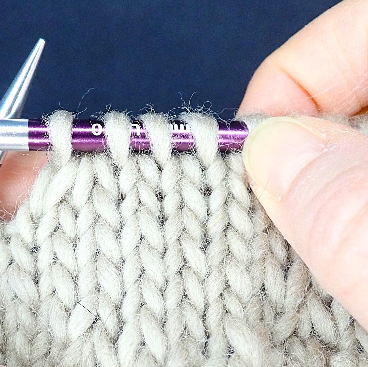 Puikoilla beige neule, jossa on juuri kavennettu 2 silmukkaa oikein yhteen.