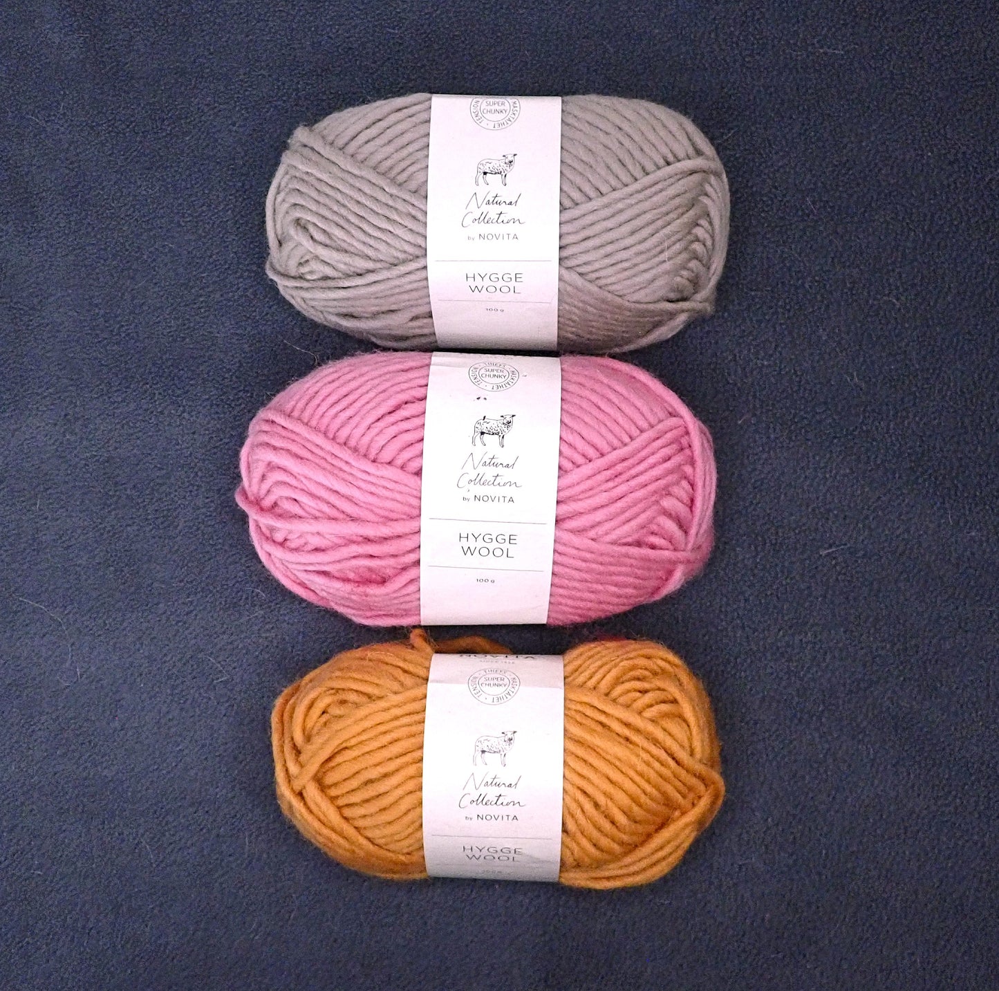 Hiekanruskea, pinkki ja oranssi kerä Novitan Hygge Wool lankaa.