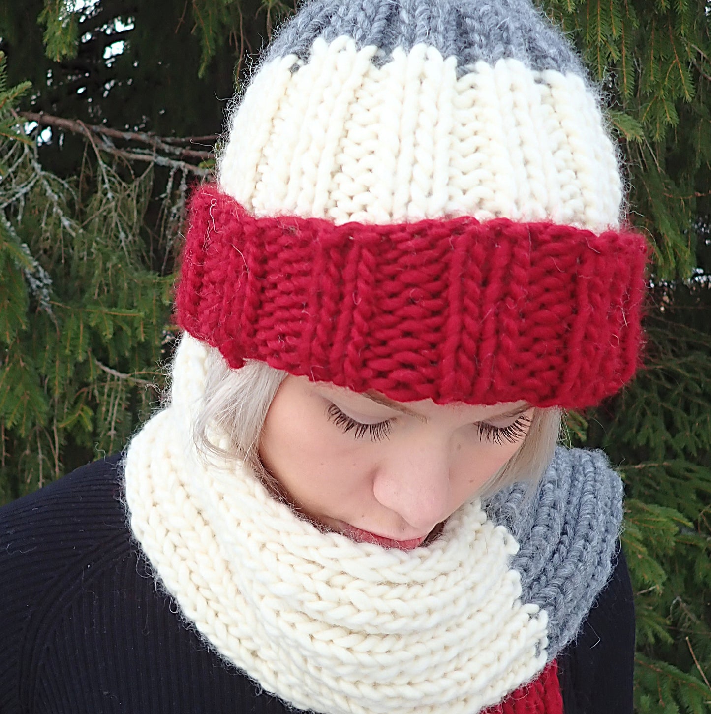 Muhkea joustinneulepipo ja kaulahuivi. Neuleissa on leveät raidat tummanpunaista, luonnonvalkoista ja harmaata.