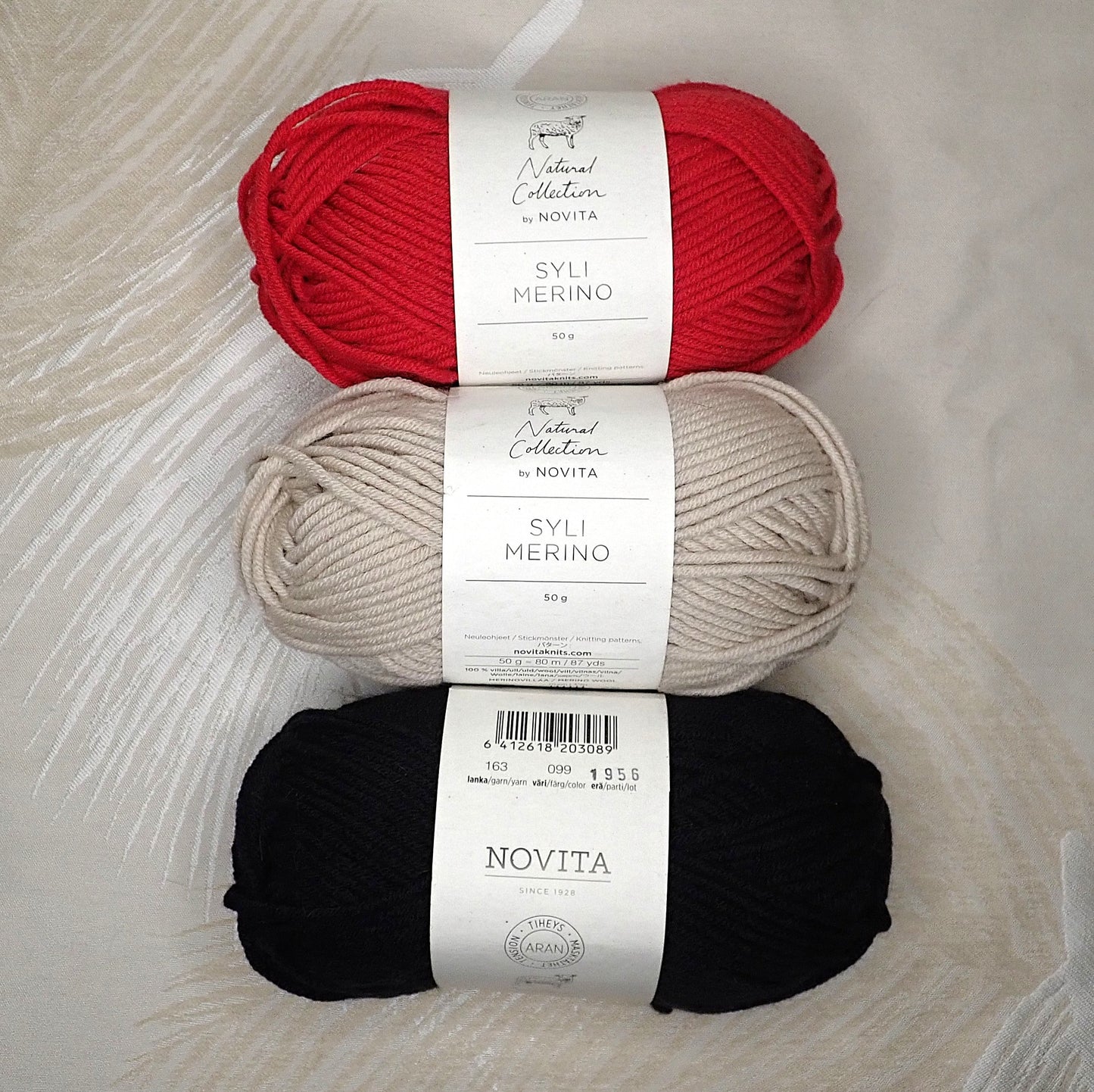 Punainen, beige ja musta kerä Novita Syli Merino -lankaa.