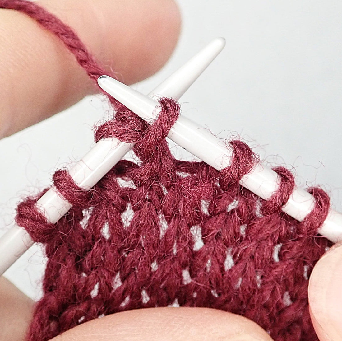 Viininpunaisesta langasta neulotaan sileää oikeaa neuletta. Tekeillä on 2 oikein yhteen kavennus.