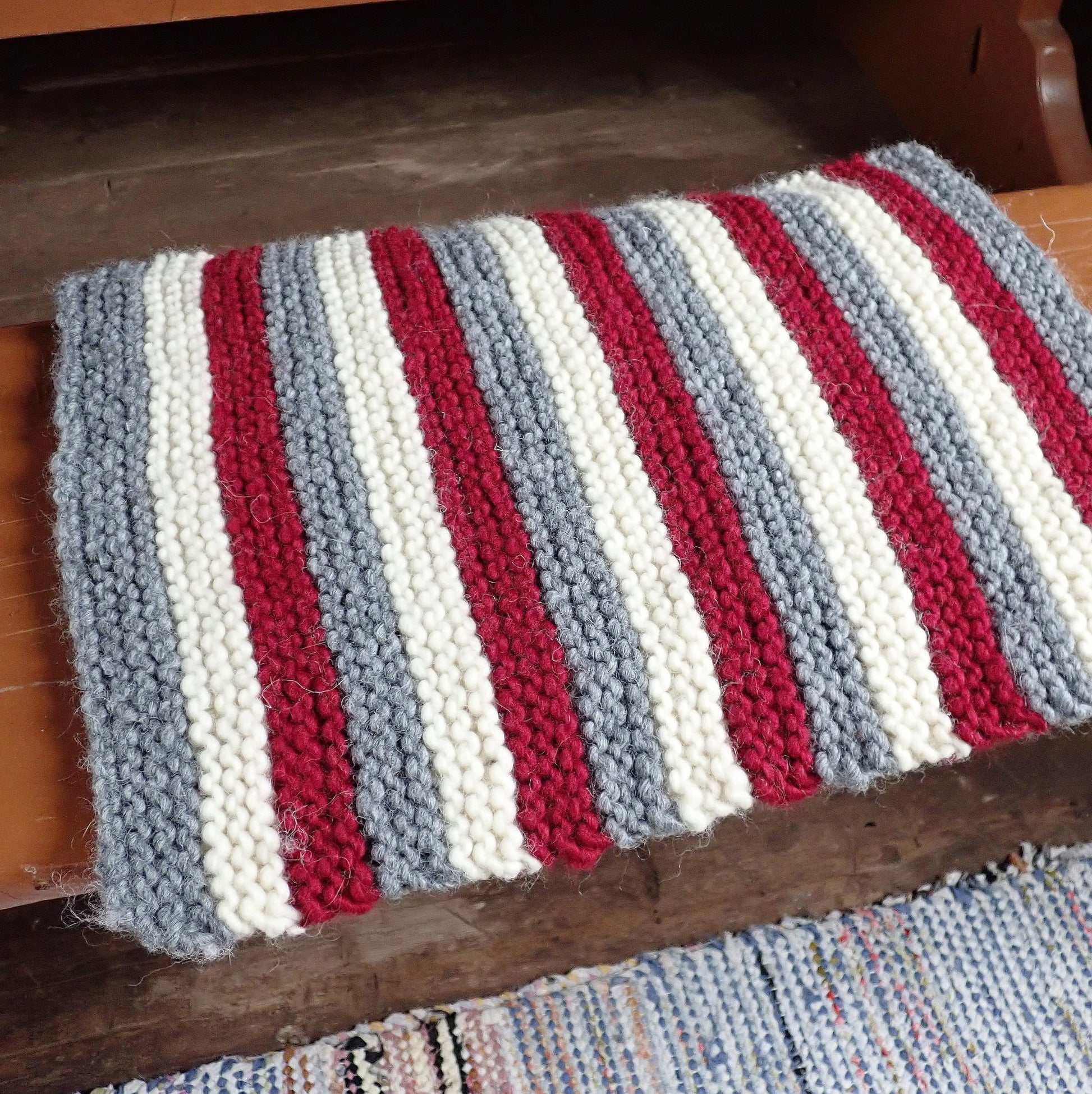 Punavalkoharmaa raidallinen istuinalusta vanhan puisen penkin päällä.