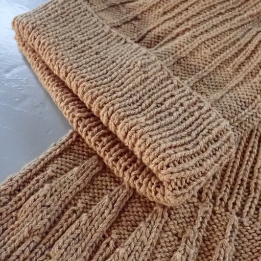 Oranssinkeltainen pipo ja kauluri, joiden pintaneule muistuttaa kantarellin helttoja.