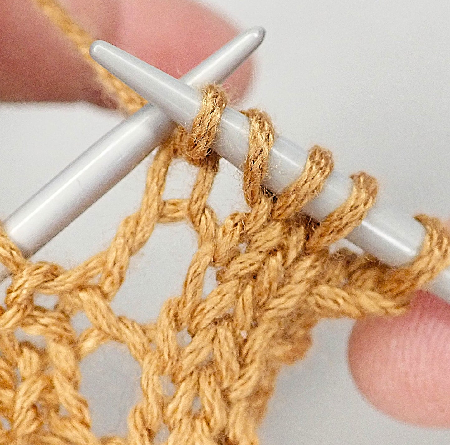 Puikoilla viljankeltaista lankaa, josta neulotaan helppoa nyörireunusta.