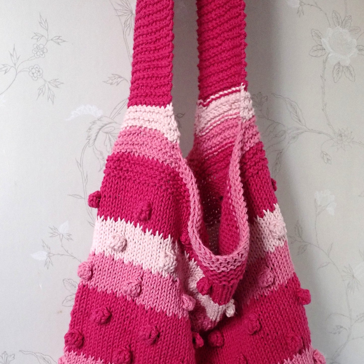 Neulotun kesäkassin yläosaa, jossa näkyy osa hihnasta. Hihna on  ainaoikeinneuletta. Kassissa on nyppyraitoja.