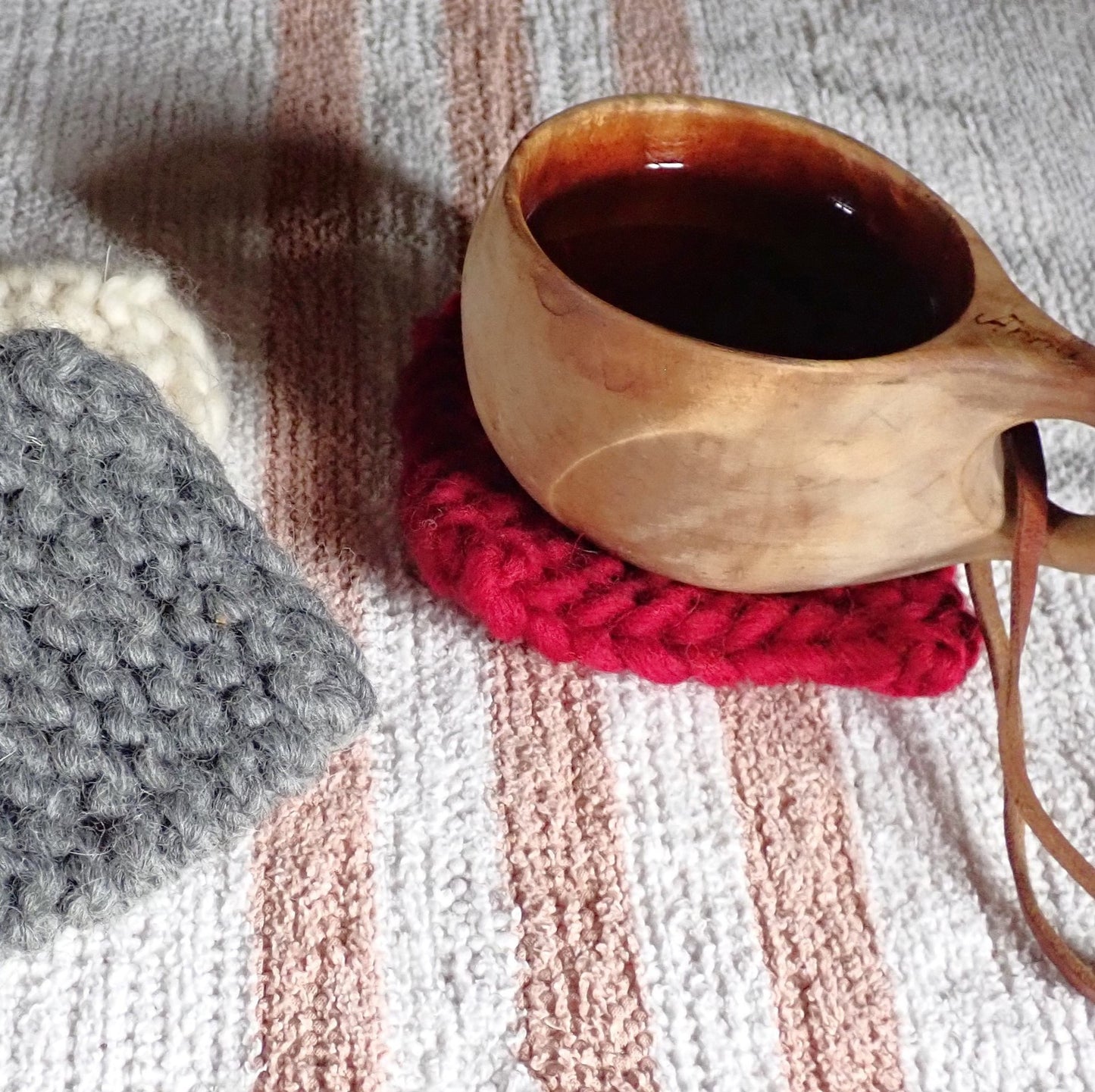 Vaalealla poppanaliinalla on kuksa, jonka alla on punainen mukinalunen. Kuksan vasemmalla puolella on puoliksi päällekkäin harmaa ja luonnonvalkoinen mukinalunen.