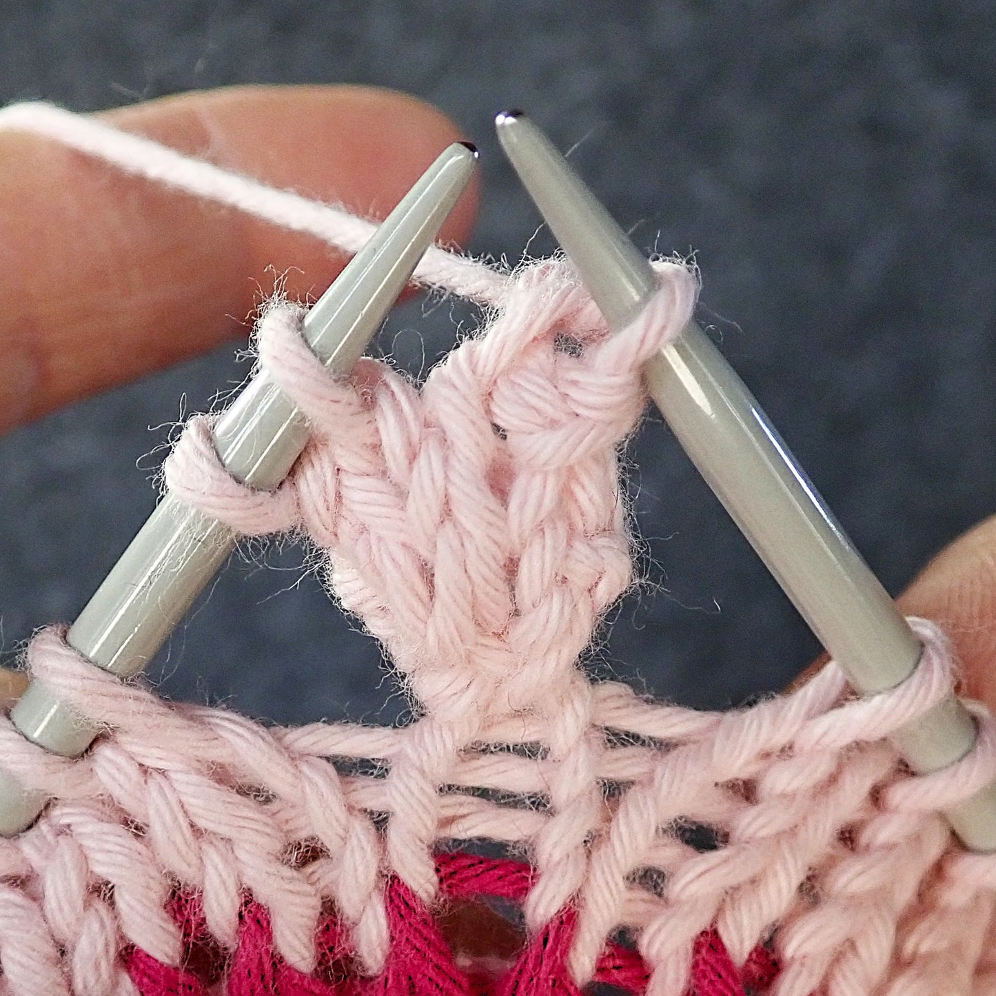 Nypyn neulomisen loppuvaihetta. Työn oikealla puolella neulotaan nypyn 2 ensimmäistä silmukkaa oikein yhteen.